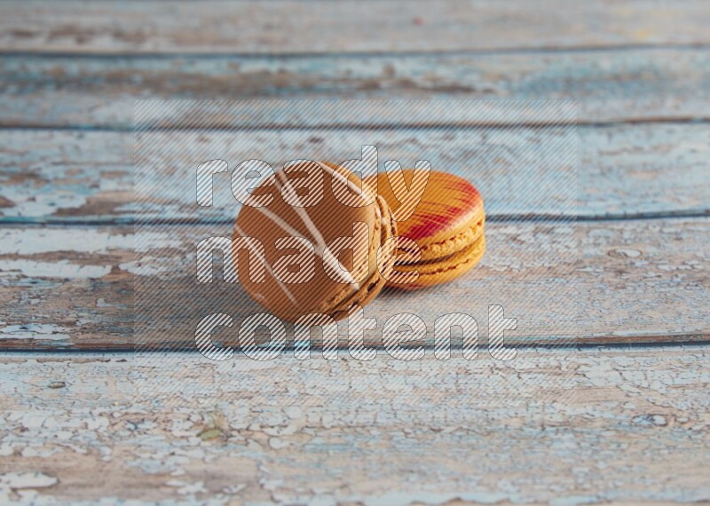 45º Shot of of two assorted Brown Irish Cream, and Orange Exotic macarons on light blue background