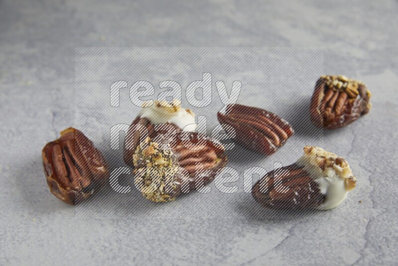 group of pecan stuffed dates plain and covered with dark and white chocolate  on alight grey background