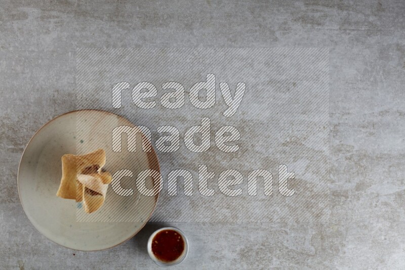 wonton cups with soy sauce ramkin on multi colored pottery on grey textured counter top