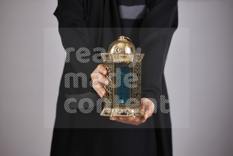 A woman in black abaya holding different ramadan lanterns in different positions