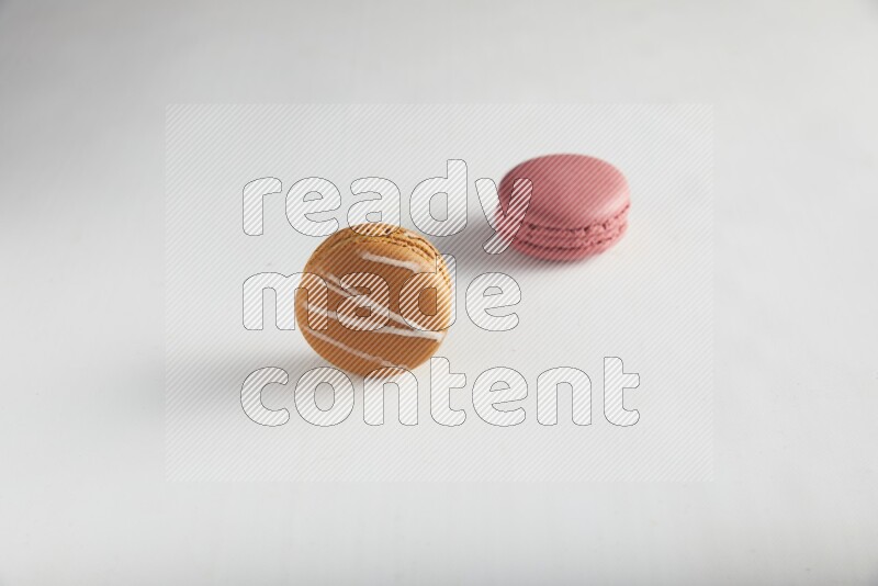 45º Shot of of two assorted Brown Irish Cream, and Pink Raspberry macarons on white background