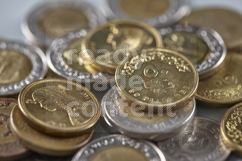 A close-up of scattered mixed Egyptian coins such as One pound, 50 and 25 piasters on grey background