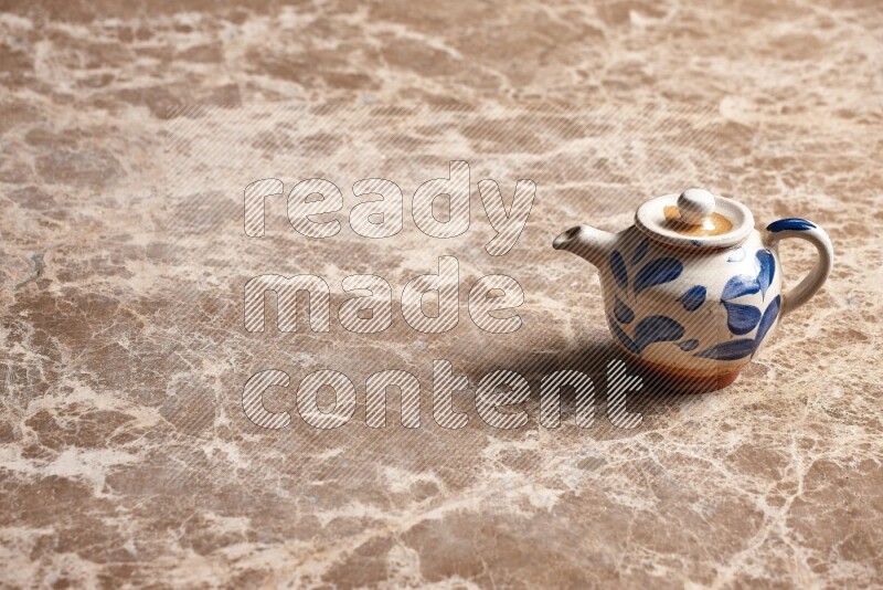 A pottery teapot on beige marble background