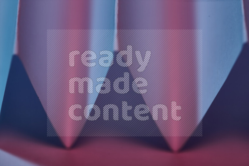 A close-up abstract image showing sharp geometric paper folds in blue and pink gradients