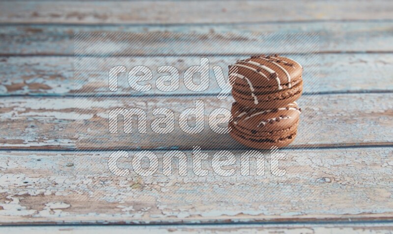 45º Shot of two Brown white  Chocolate Caramel macarons on light blue wooden background