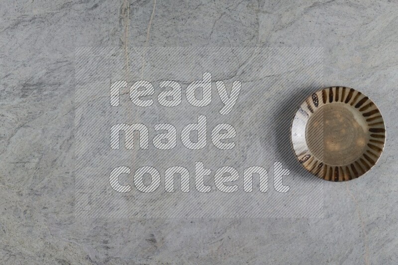 A multicolored pottery plate on grey marble background
