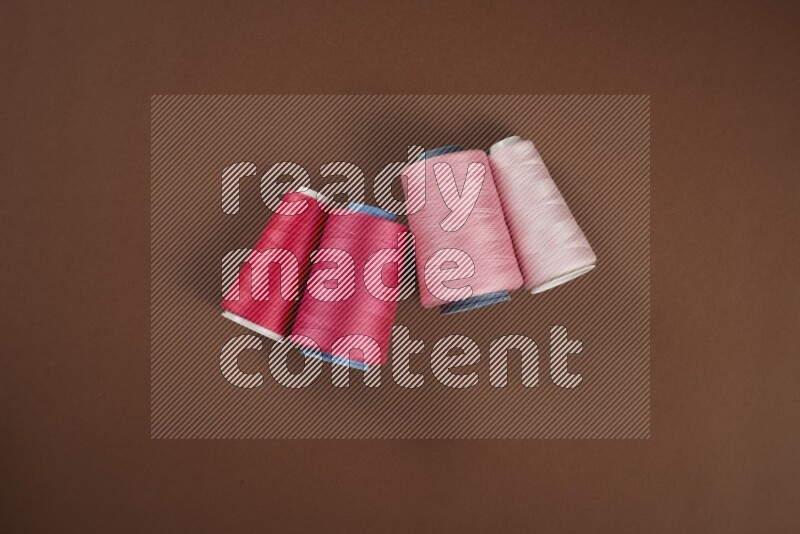 مجموعة من أدوات الخياطة والتفصيل زهرية اللون على خلفية بنية