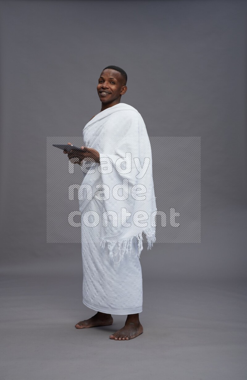 A man wearing Ehram Standing working on tablet on gray background