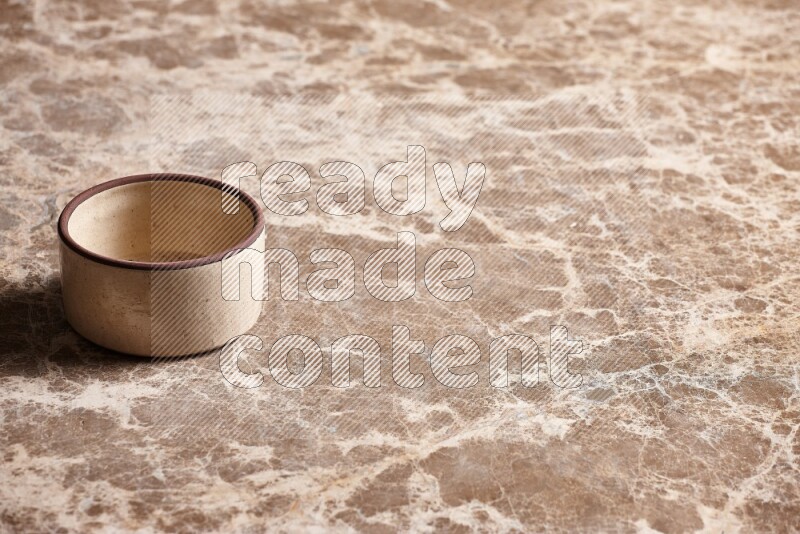 A beige pottery oven bowl on beige marble background