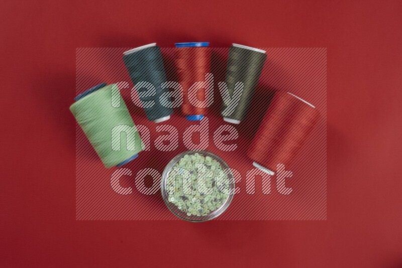 A green and red collection of sewing and tailoring tools arranged on a red background