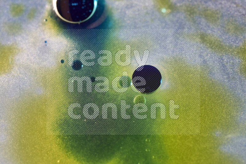 لقطات مقربة لقطرات ألوان مائية صفراء وزرقاء وخضراء على سطح الزيت على خلفية بيضاء