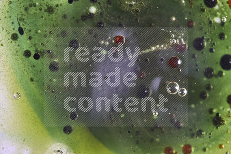 لقطات مقربة لقطرات ألوان مائية حمراء وخضراء وزرقاء على سطح الزيت على خلفية خضراء