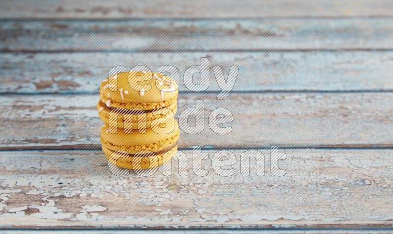 45º Shot of two Yellow Piña Colada macarons on light blue wooden background