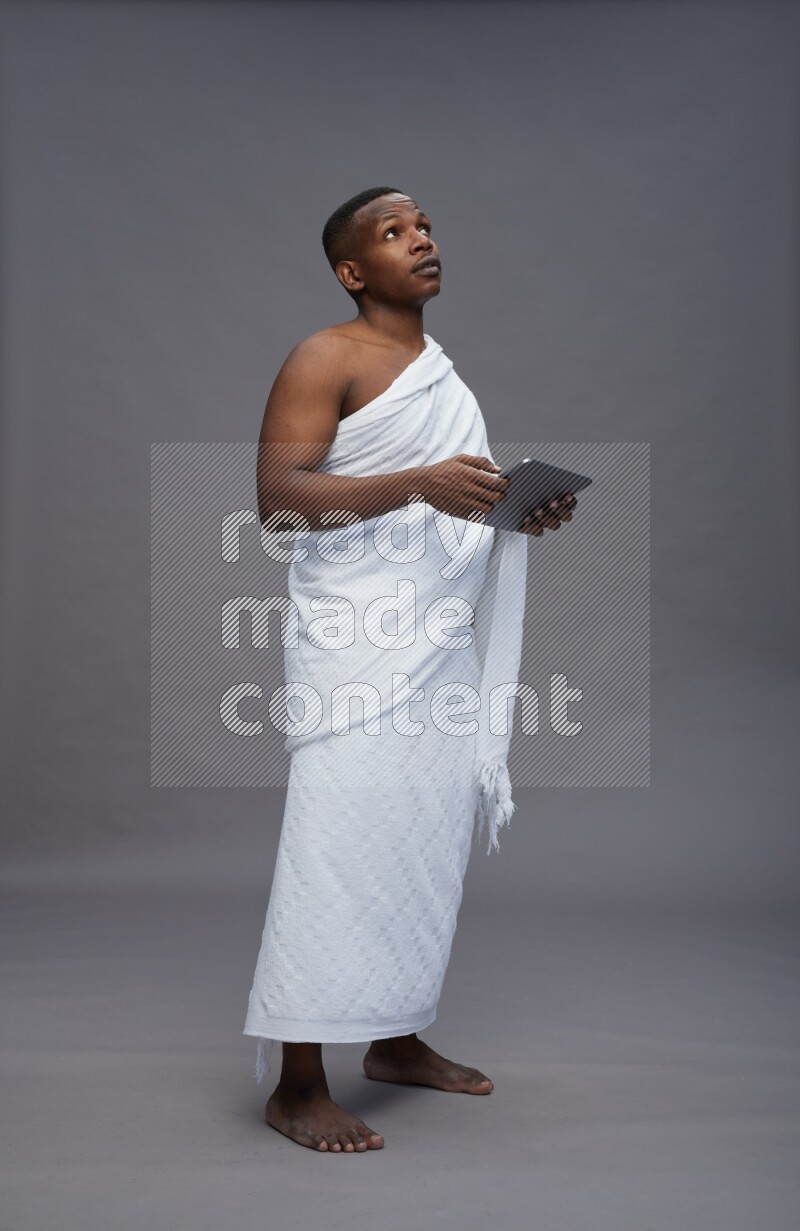 A man wearing Ehram Standing working on tablet on gray background