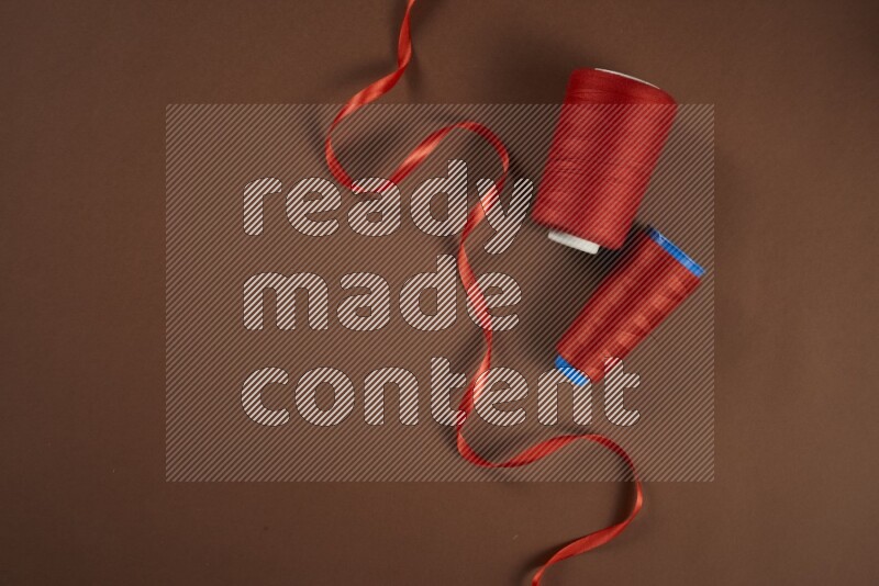 A red collection of sewing and tailoring tools arranged on a brown background