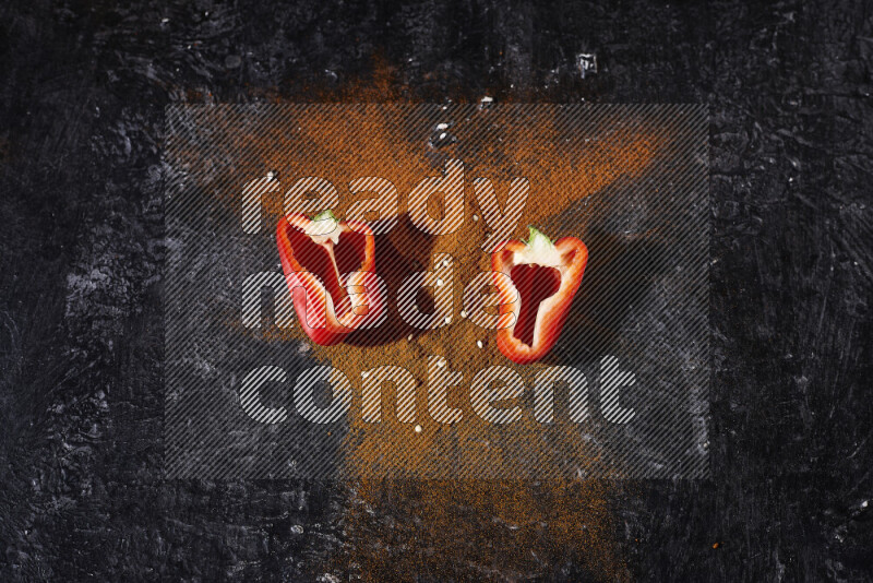 حفنة من بودرة البابريكا مع نصفين من الفلفل الأحمر الحلو على خلفية سوداء