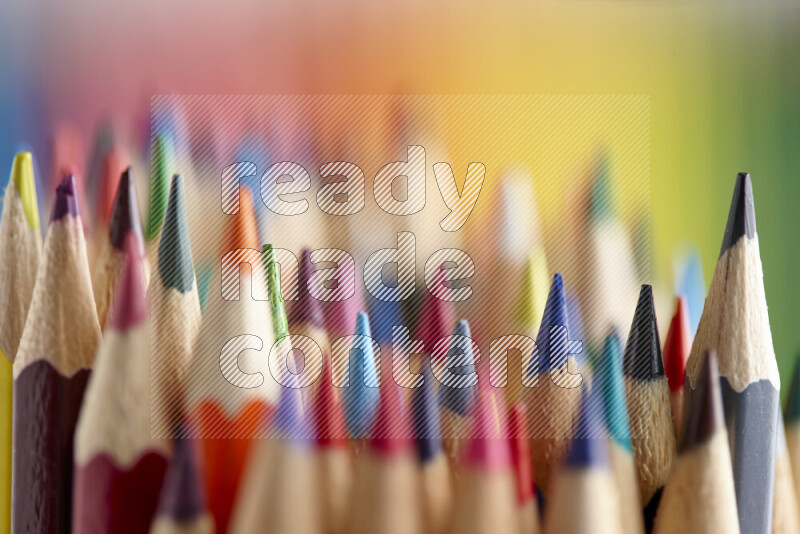 The image captures a close-up of sharpened colored pencils on multicolored background