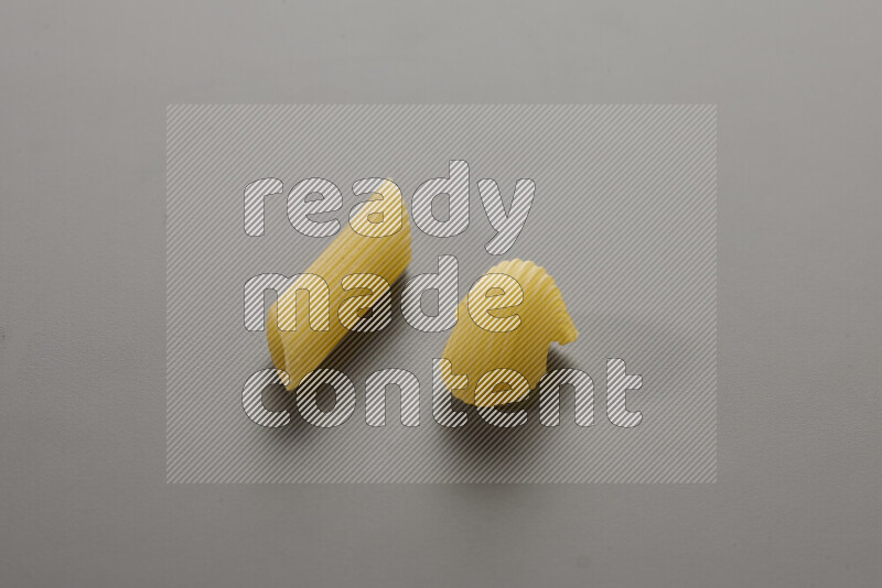 Penne pasta with other types of pasta on grey background