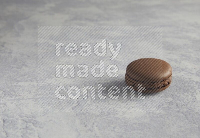 45º Shot of Brown Dark Chocolate macaron on white  marble background