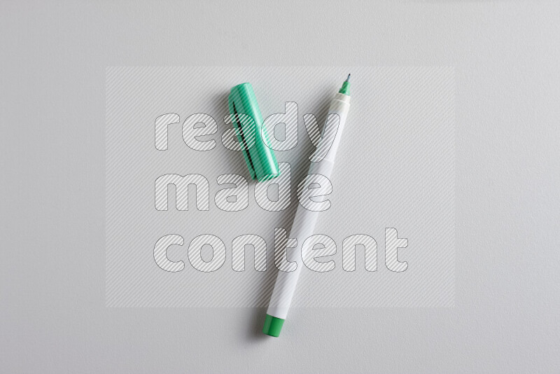 A close-up showing an open single coloring pen with a cap on grey background