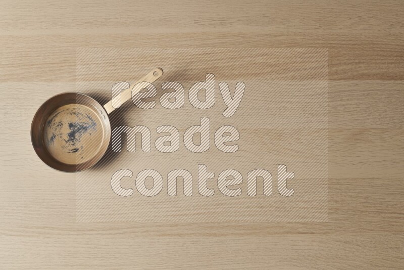 A small copper pan on light wooden background