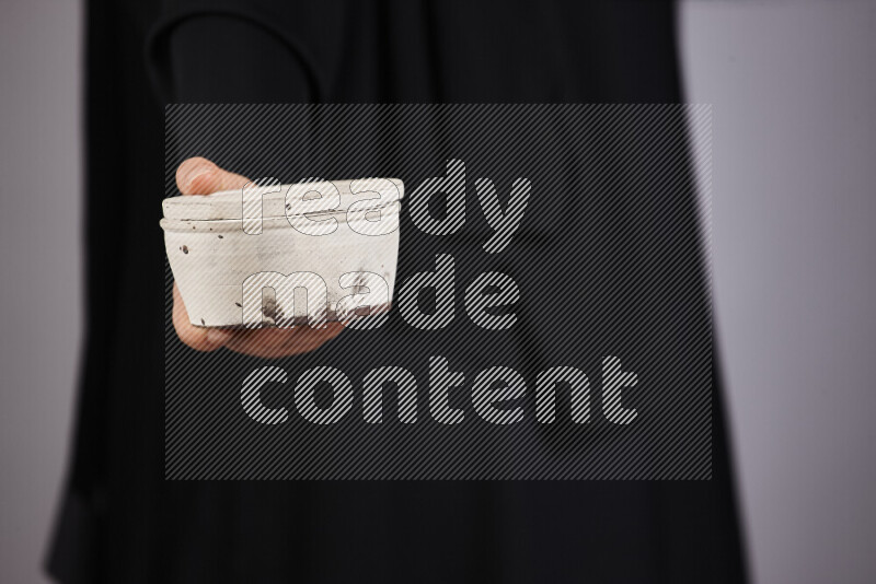 امرأة ترتدي عباءة سوداء تحمل أدوات فخارية مختلفة في أوضاع متعددة