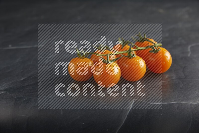 Orange cherry tomato vein on a textured black slate background 45 degree