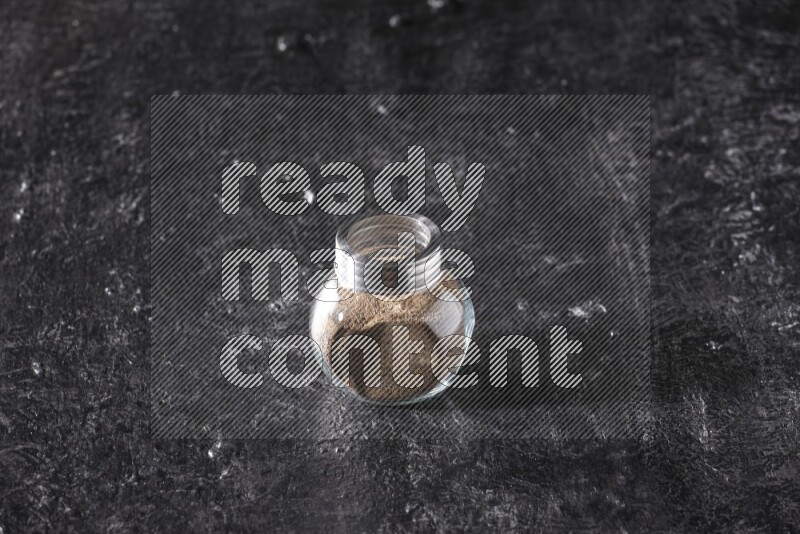 بودرة الفلفل الأسود في وعاء زجاجي علي خلفية سوداء