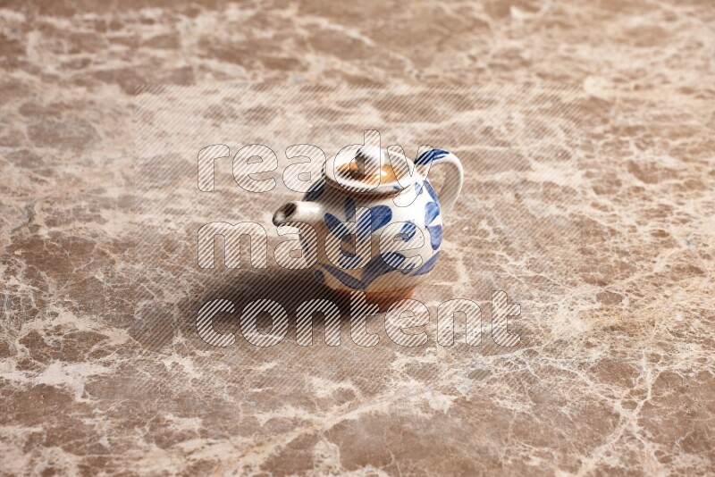 A pottery teapot on beige marble background