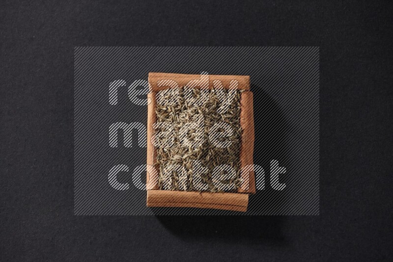 A single square of cinnamon sticks full of cumin on black flooring