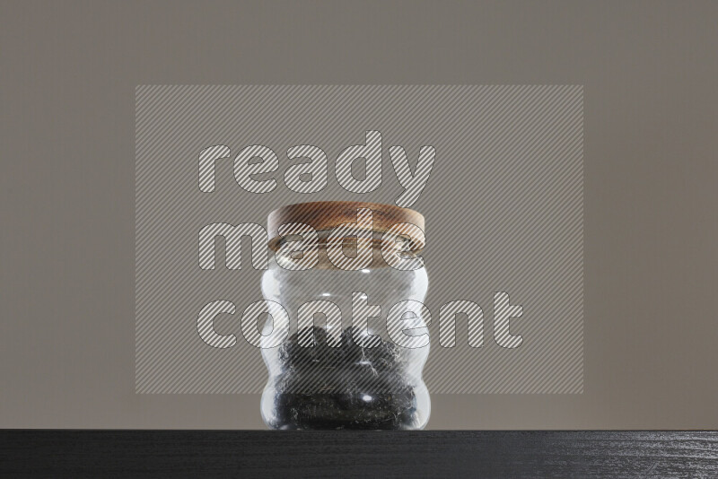 قراصيا مجففة في وعاء زجاجي على خلفية سوداء