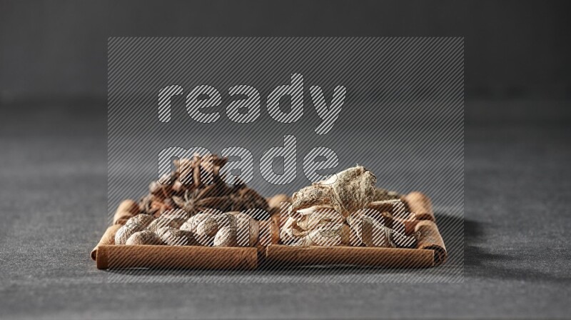 4 squares of cinnamon sticks full of star anise, cumin, dried ginger and nutmegs on black flooring