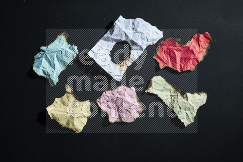 Burnt multicolored paper on black background