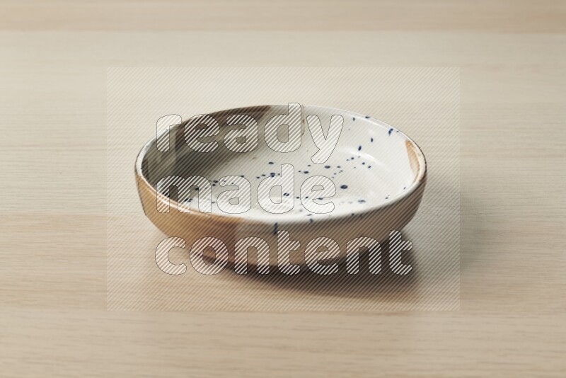 A multicolored pottery bowl on light wooden background