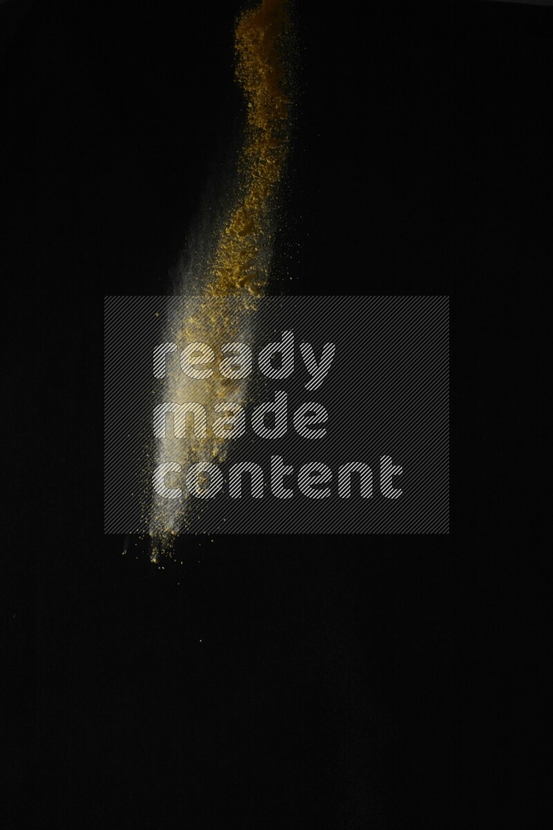 A side view of yellow powder explosion on black background