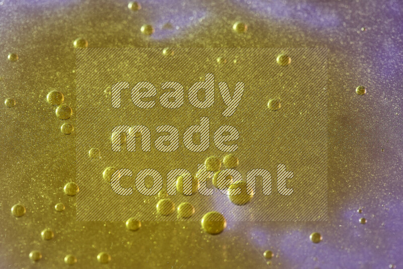 Close-ups of abstract yellow watercolor drops on oil Surface on pink background