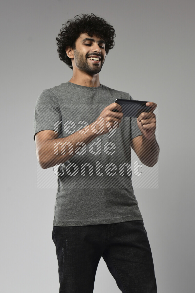 A man wearing casual standing and gaming on the phone on white background