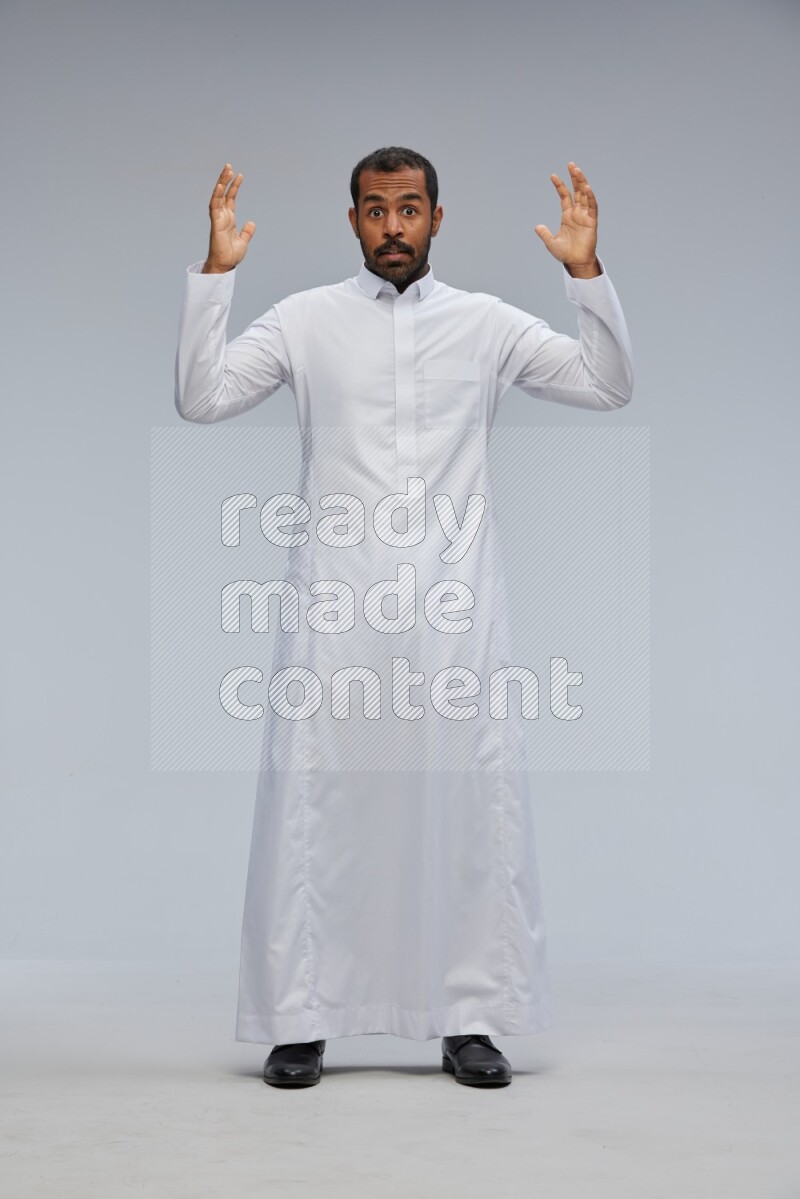 Saudi man Wearing Thob standing interacting with the camera on Gray background