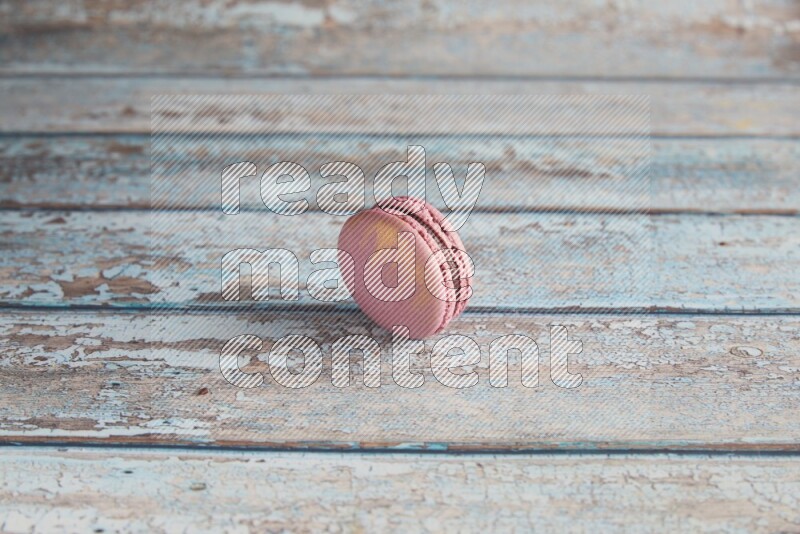 45º Shot of Purple Strawberry macaron on light blue wooden background