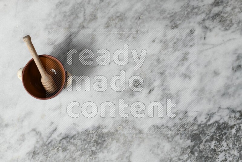 Decorative Pottery Pot with wooden honey handle in it, on grey marble flooring, Top View