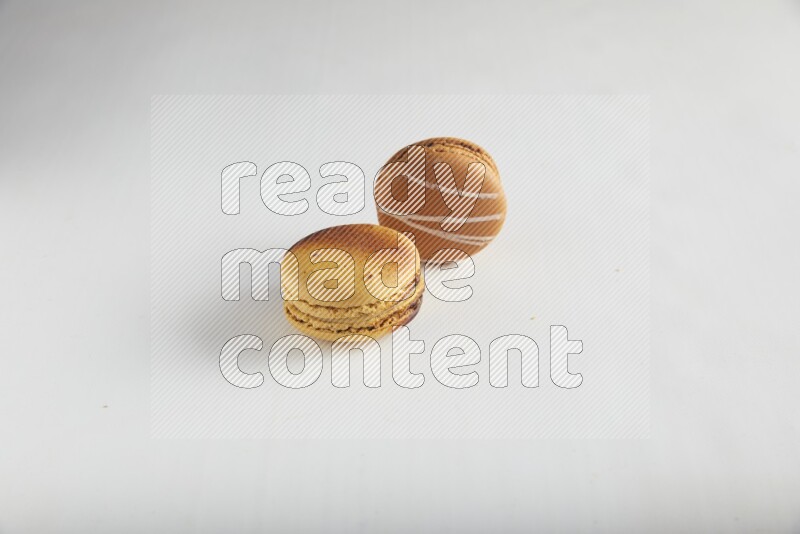 45º Shot of of two assorted Brown Irish Cream, and Yellow Crème Brulée macarons on white background