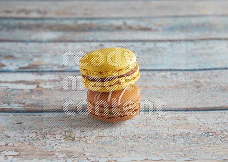 45º Shot of of two assorted Brown Irish Cream, and Yellow Lemon macarons on light blue background