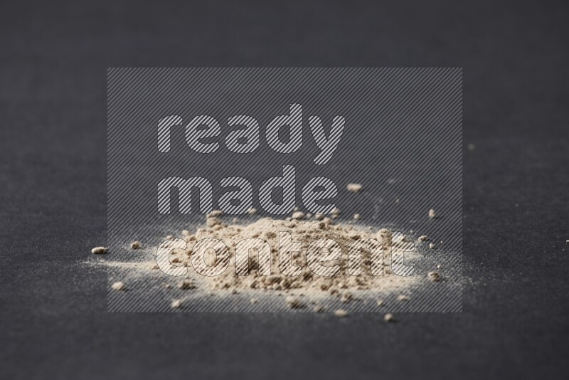A small pile of garlic powder on a black background