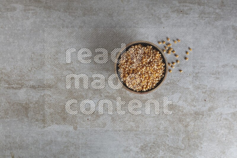 corn kernel in a wooden bowl on a grey textured countertop