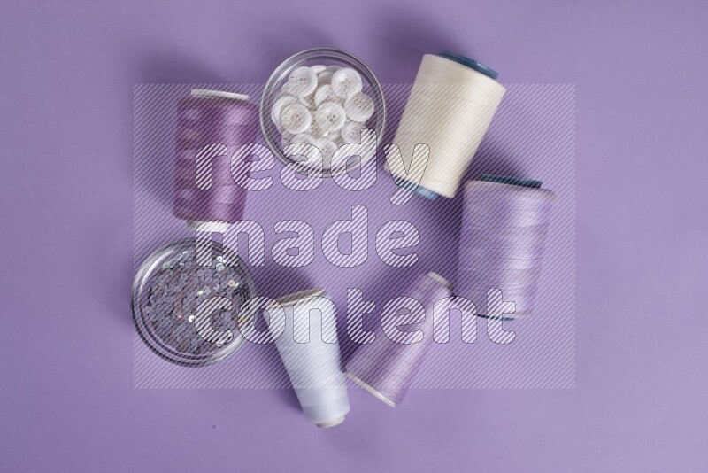 A white and purple collection of sewing and tailoring tools arranged on a purple background