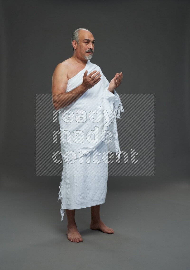 A man wearing Ehram Standing dua'a on gray background